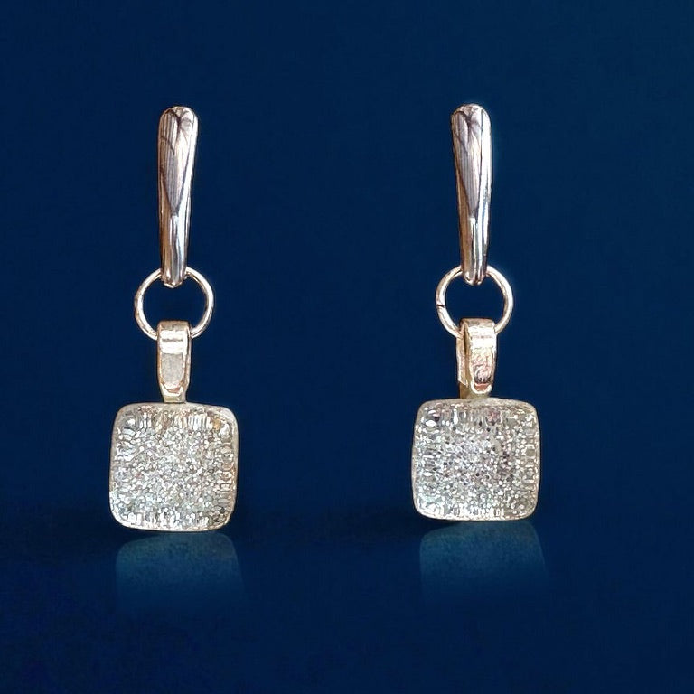 Pair of silver square earrings on a dark blue background