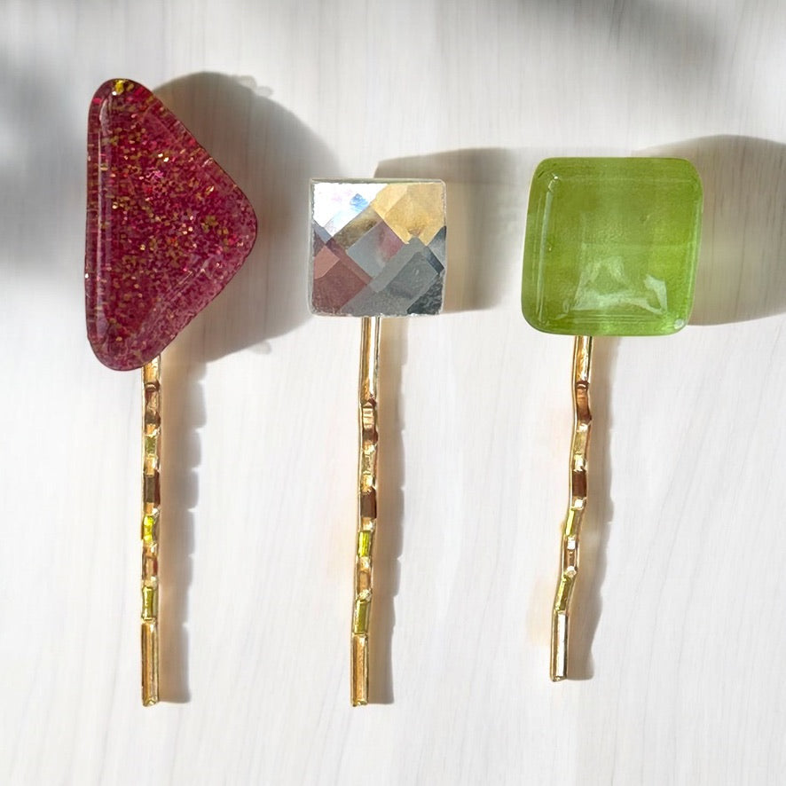 Three hair pins with colorful glass stones on a white background