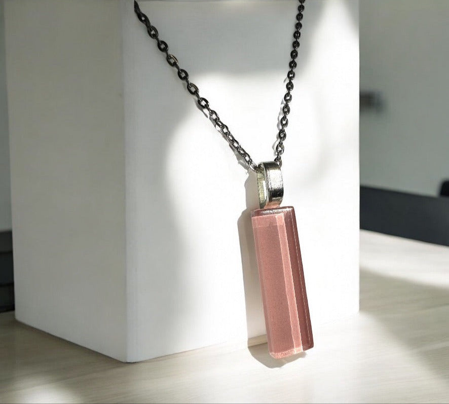 Necklace with a pink pendant on a white stand