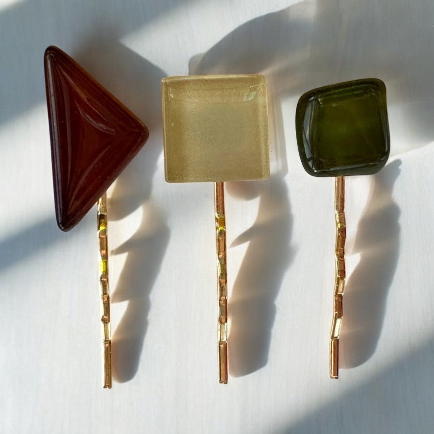 Set of decorative glass hair pins with square and triangular shapes on a light background