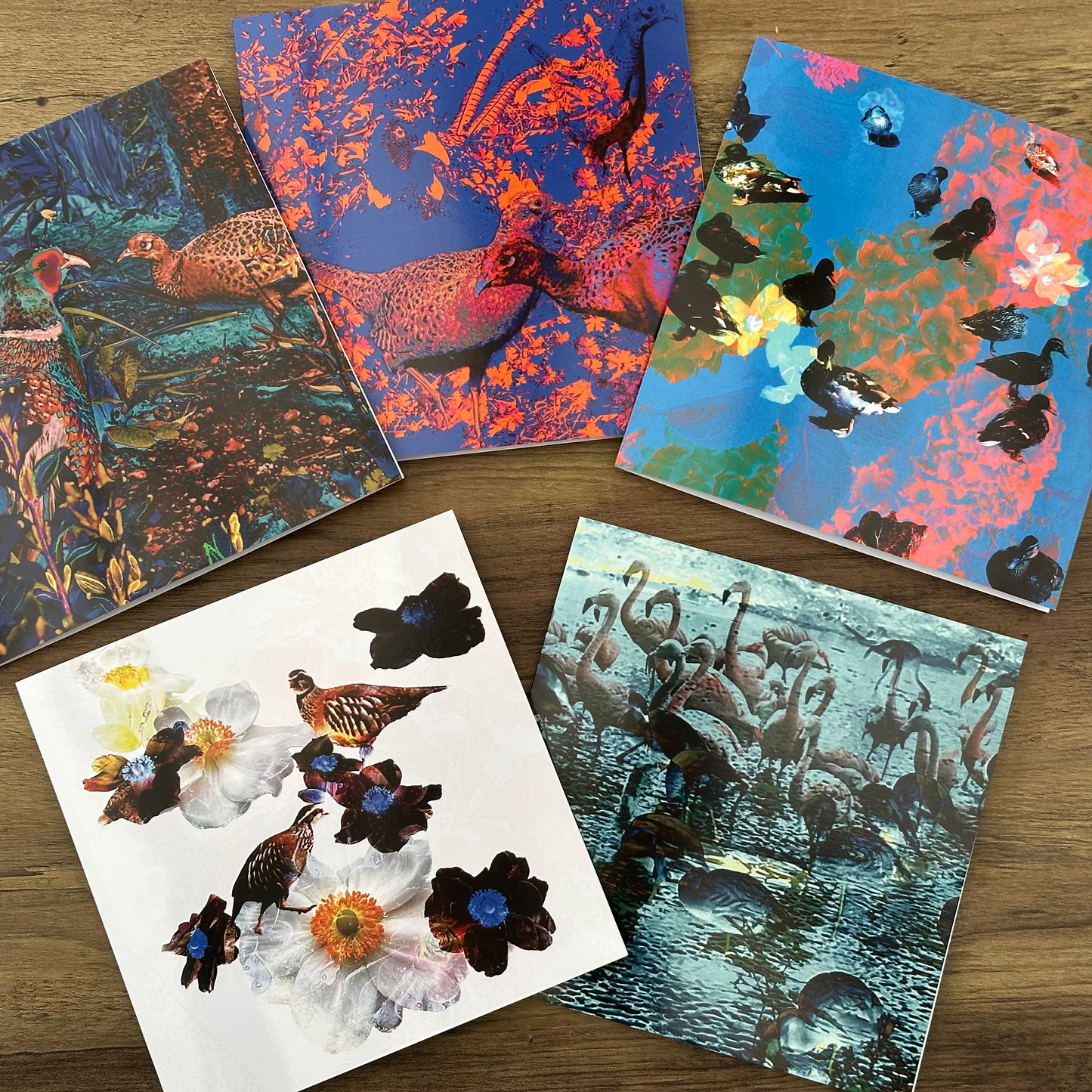 Five colorful greeting cards with nature-themed designs on a wooden surface