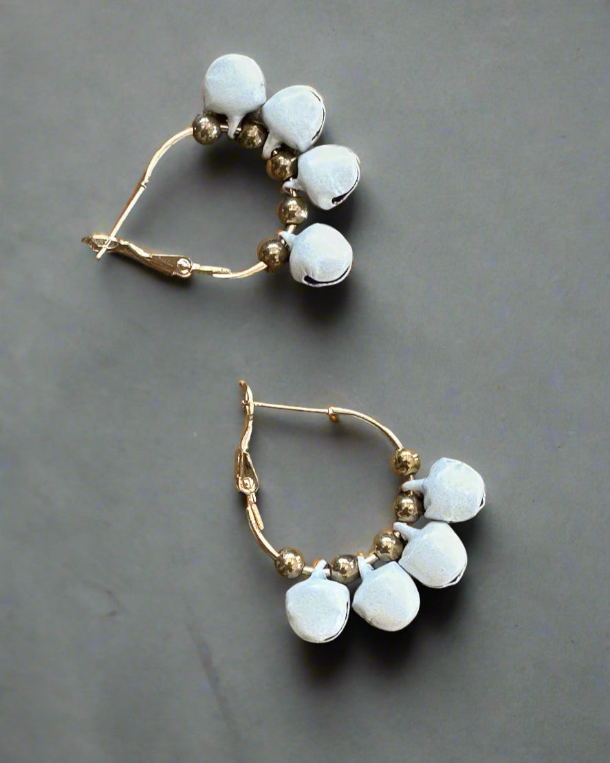 Gold hoop earrings with white bells-beads on a gray background