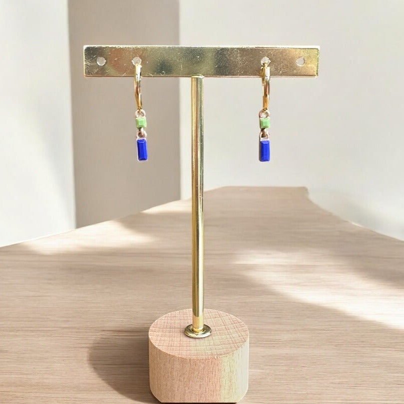 Gold earring stand with colorful earrings on a wooden surface