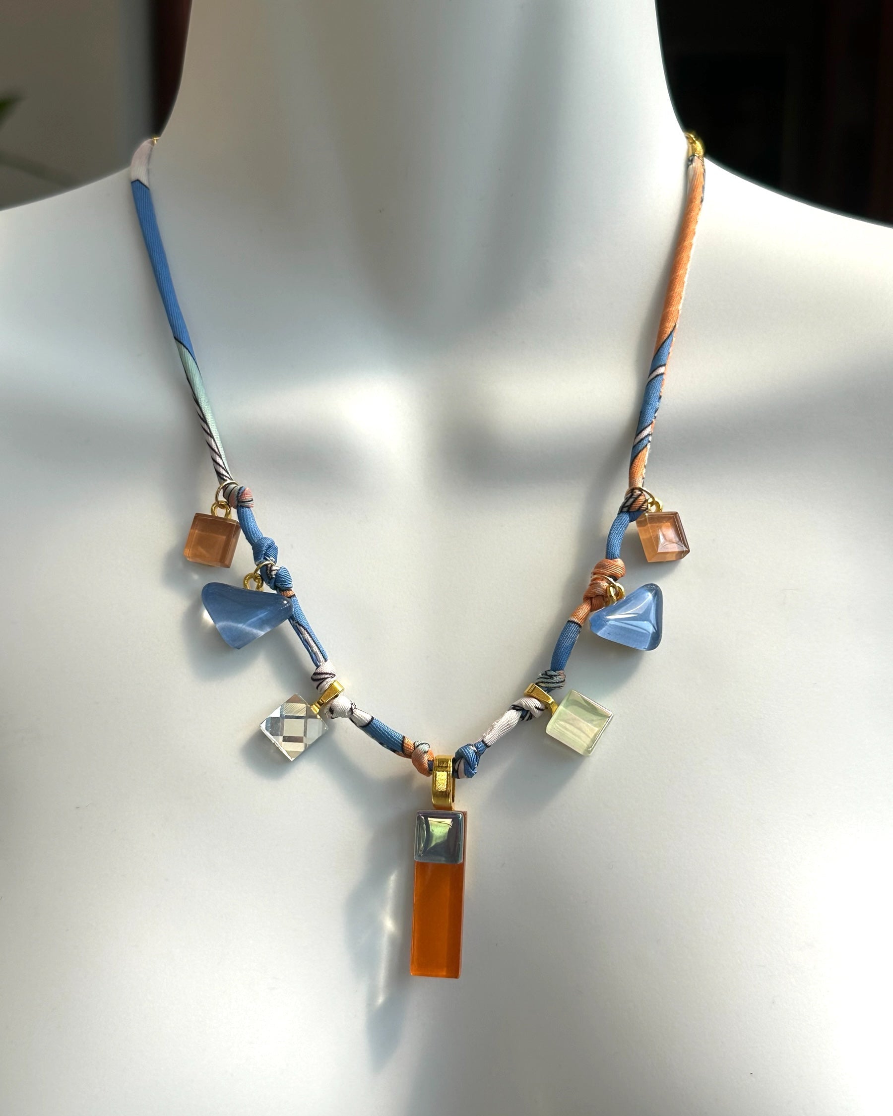 Necklace with blue and brown glass charms on a mannequin