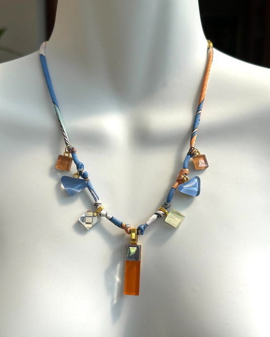 Necklace with blue and brown glass charms on a mannequin