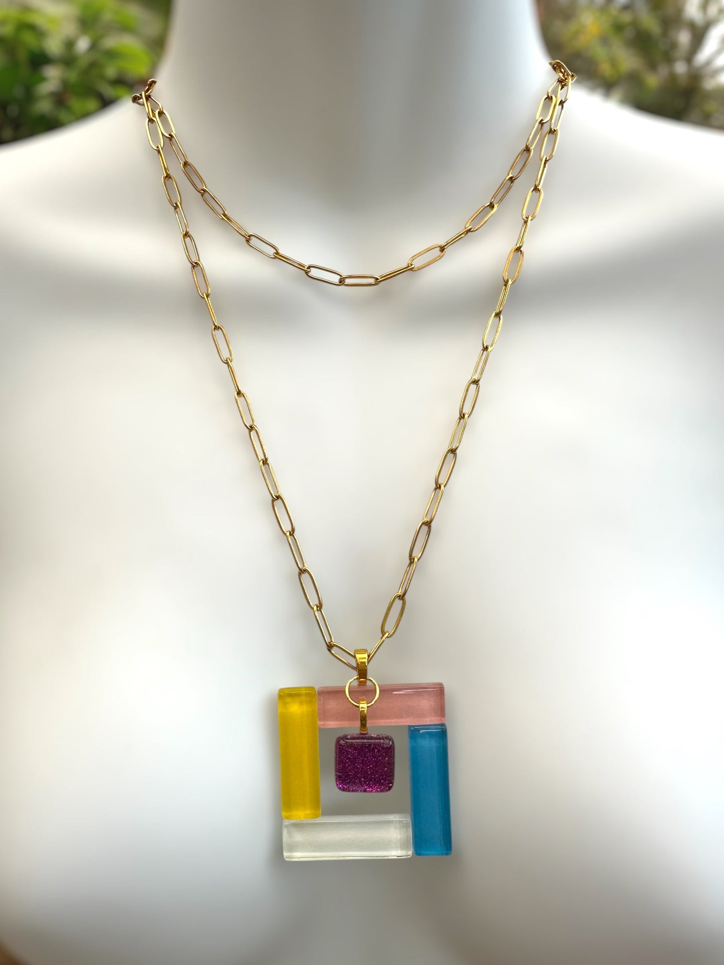 Fused glass necklace with a colorful square pendant on a mannequin