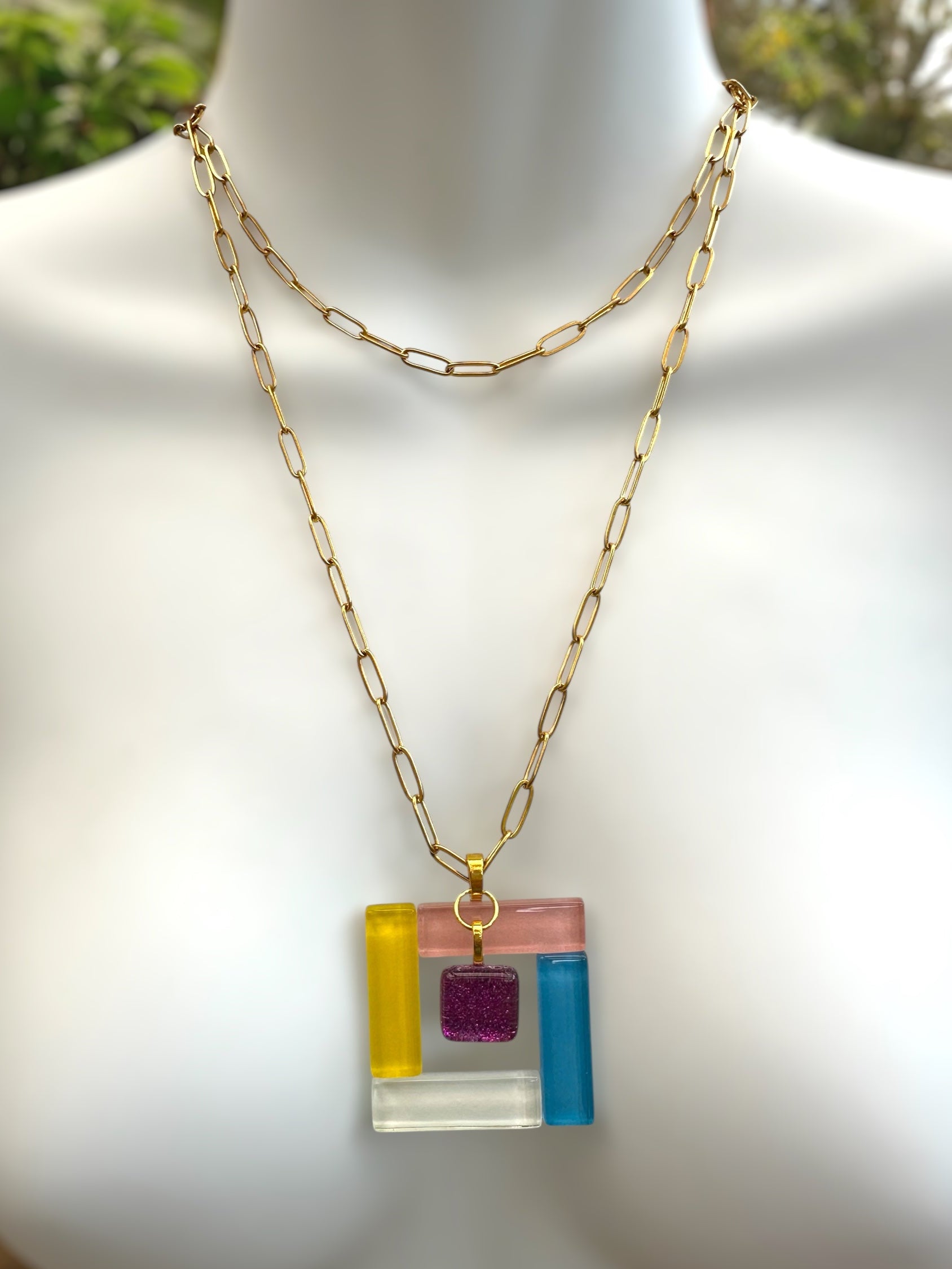 Fused glass necklace with a colorful square pendant on a mannequin