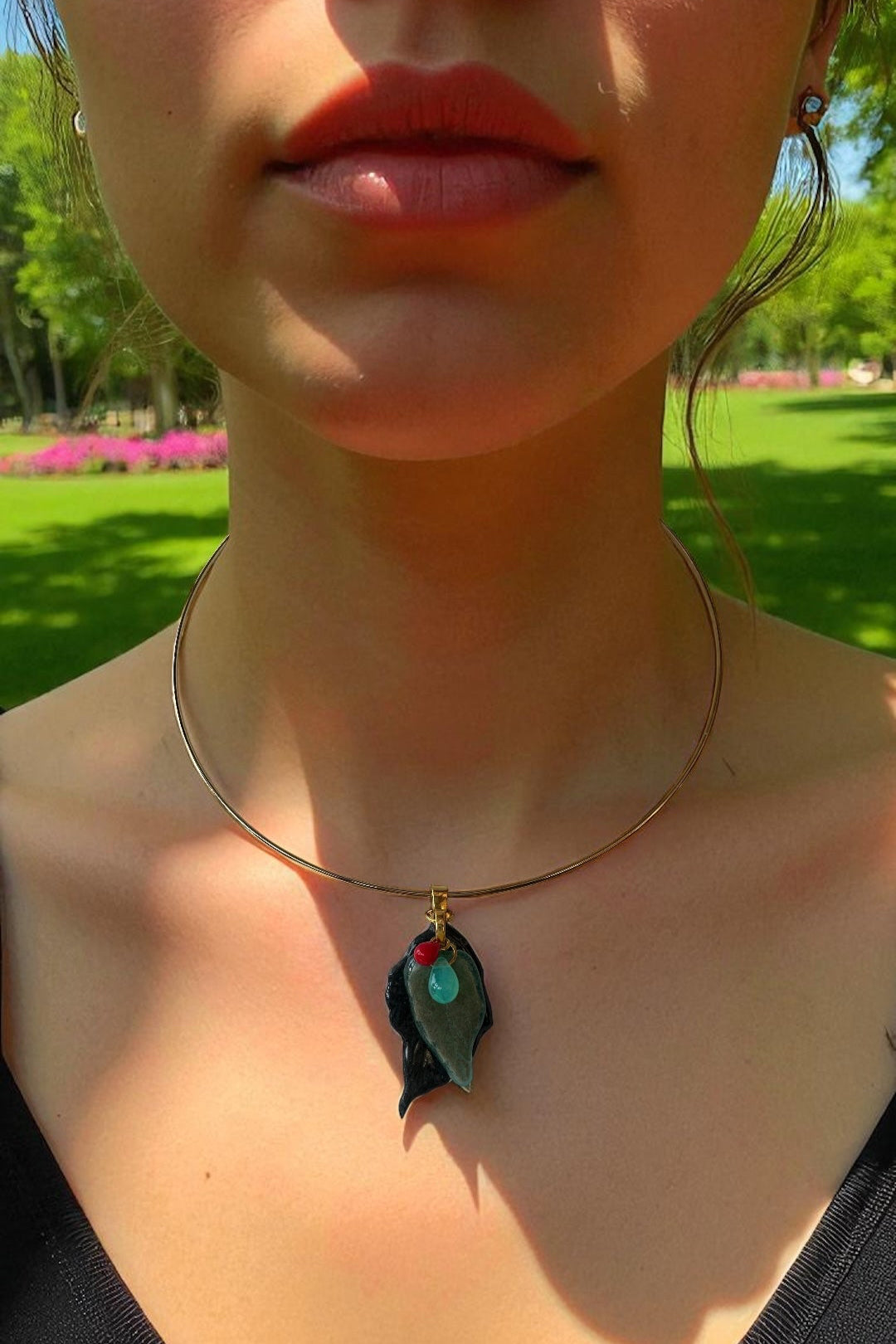 Necklace with a glass leaf pendant worn by a person outdoors