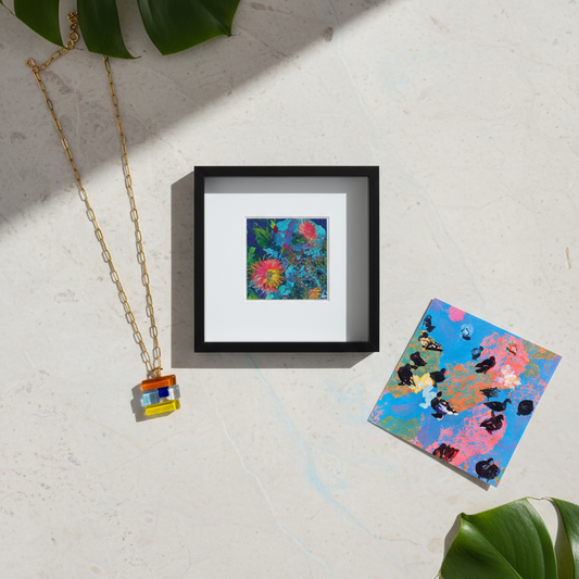 Framed and loose abstract art pieces on a light surface with leaves.